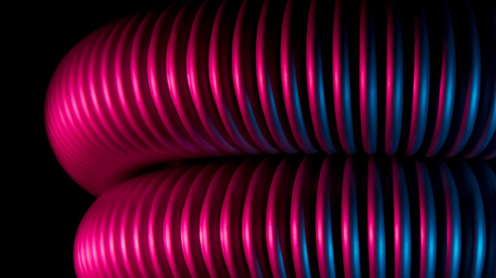 Close up of coiled pipes with blue and pink lights.