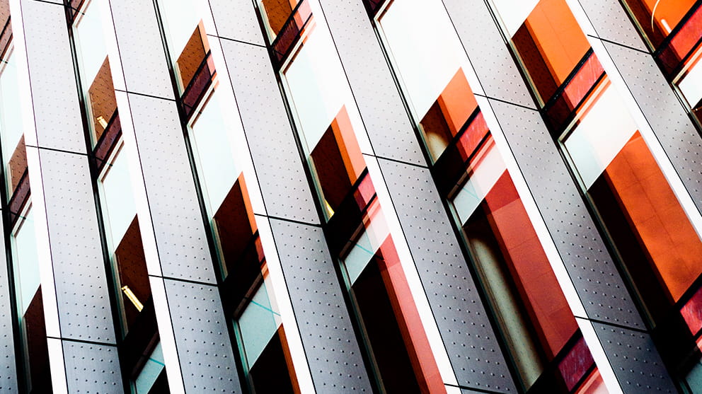 Close up of an office building with white cladding and red metalwork