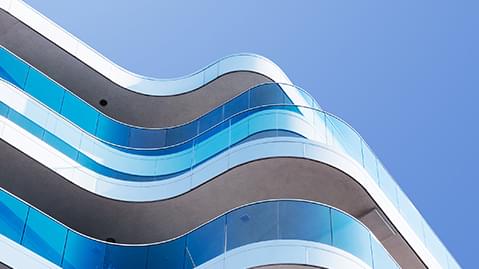 Modern building with blue glass and curving balcony.