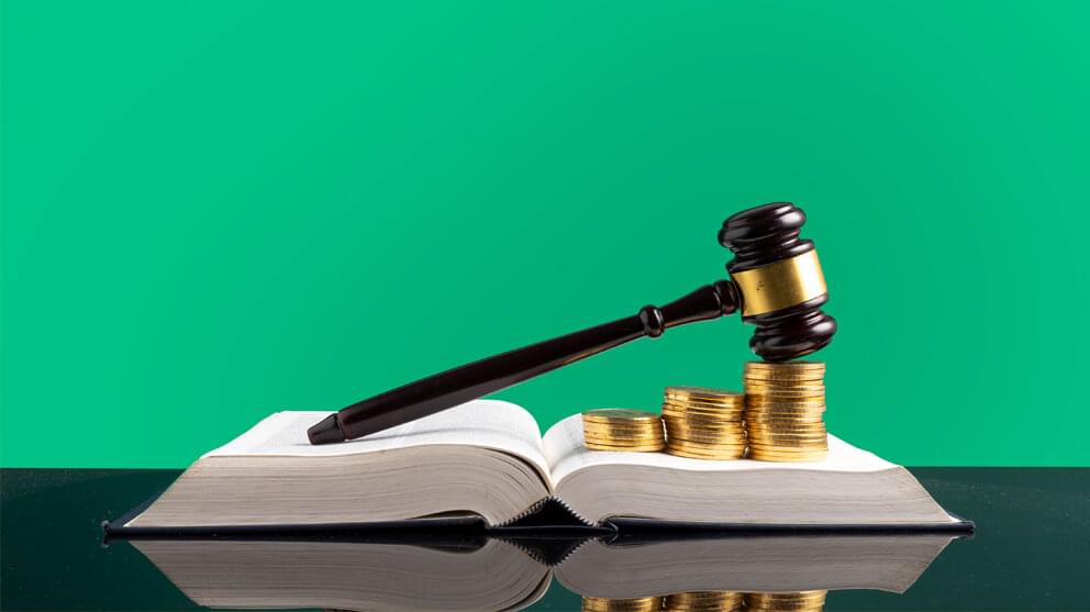 Stack Of Coins With Gavel Over Open Book