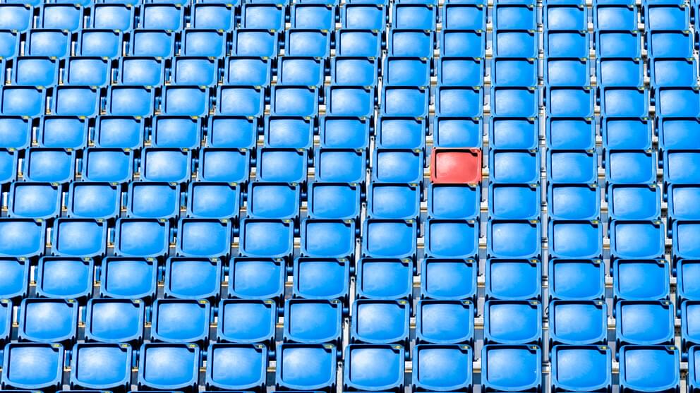 Empty red chair in middle of blue chairs