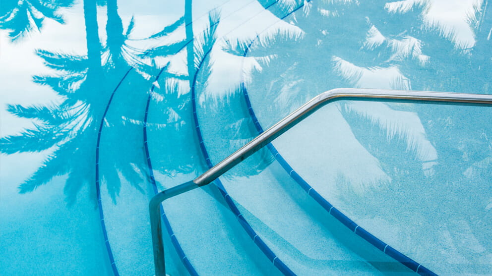 Reflection of palm trees over swimming pool with curved steps