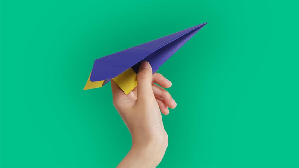 Hand Holding Blue Paper Airplane on green background