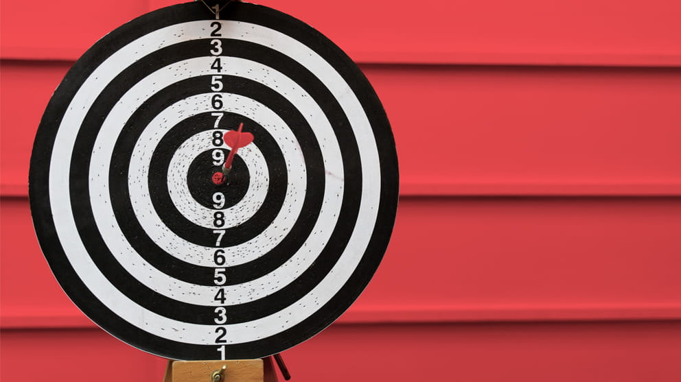 Hitting the centre of target with dart on red background 