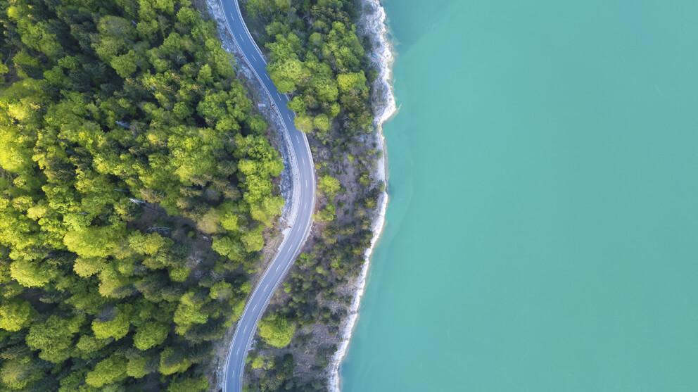 Aerial view on turquoise lake and forest with road