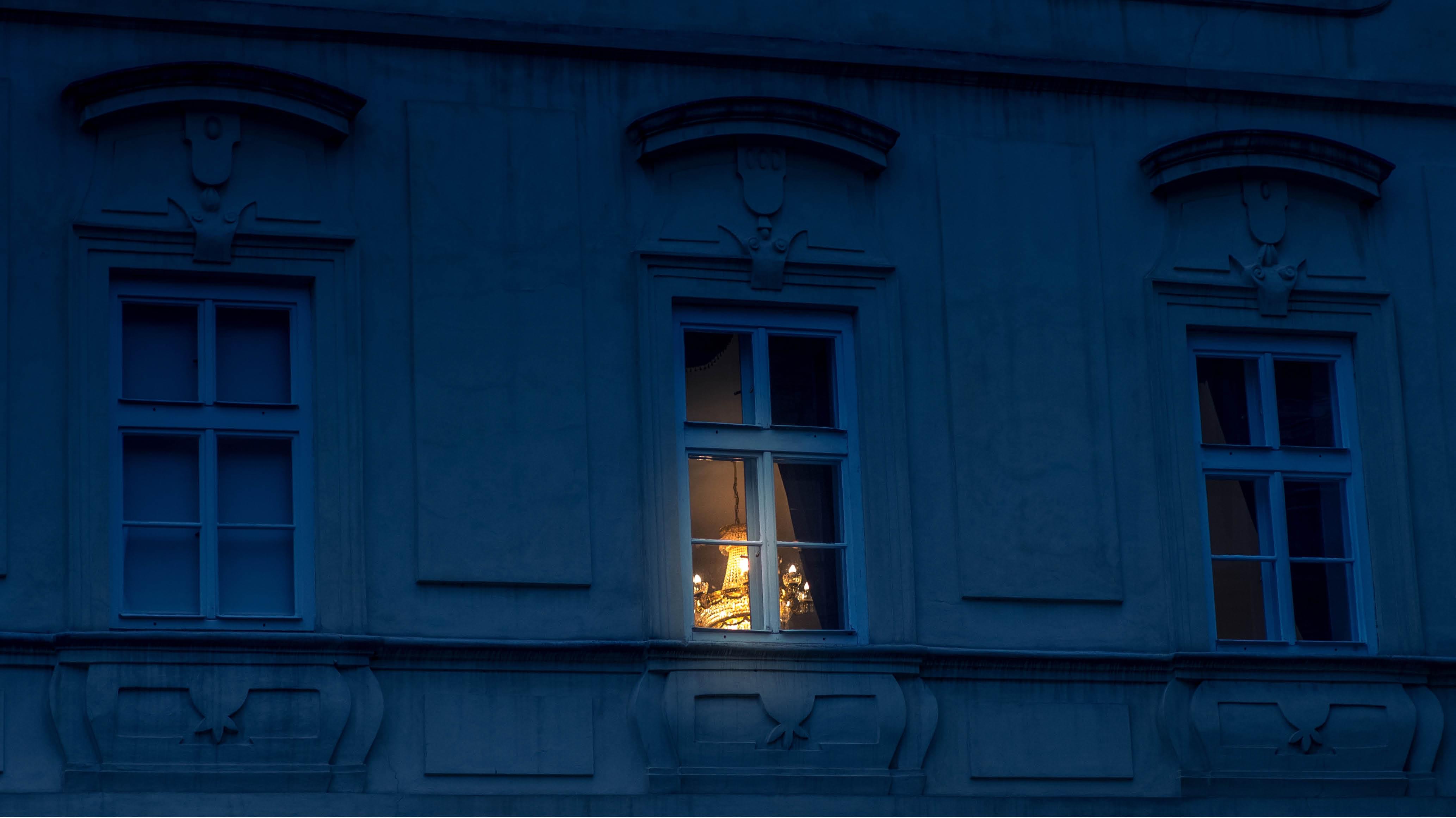 A photo of a window at night with a light shining through the window.